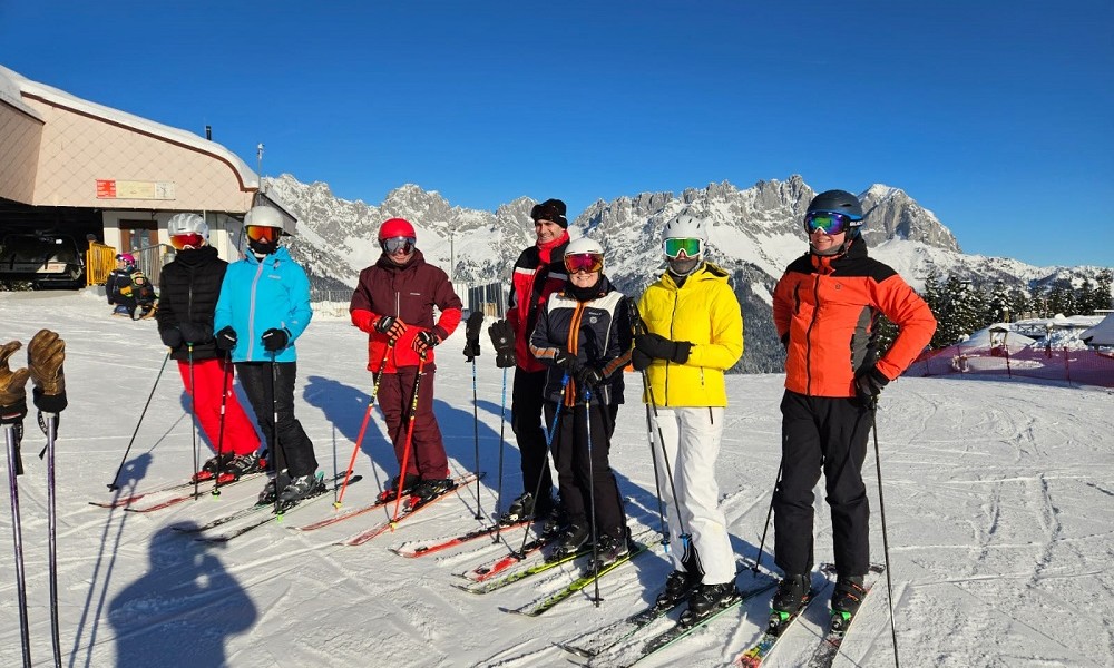 Gruppe Hotelgästen genießt einen entspannten Skitag mit Hotelchef Hans 