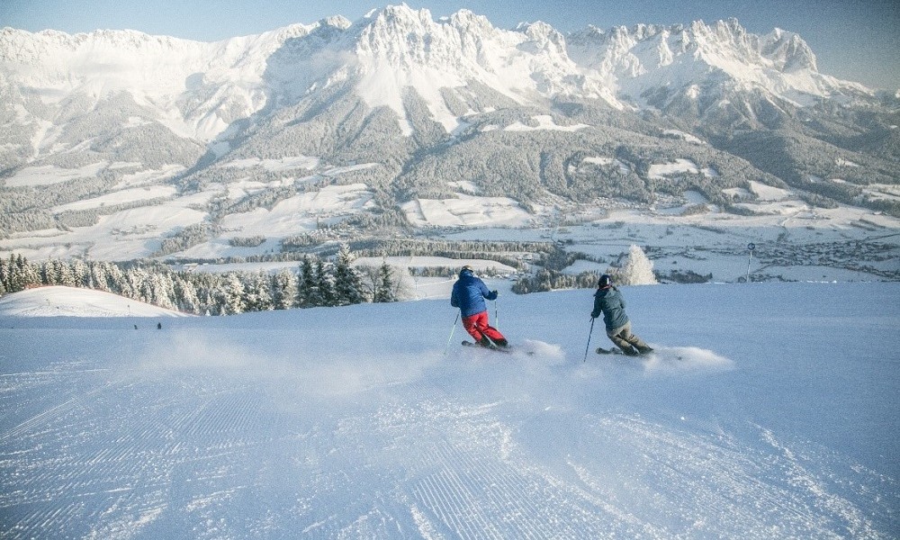 Zwei Skifahrer rasen die schneebedeckte Piste runter 